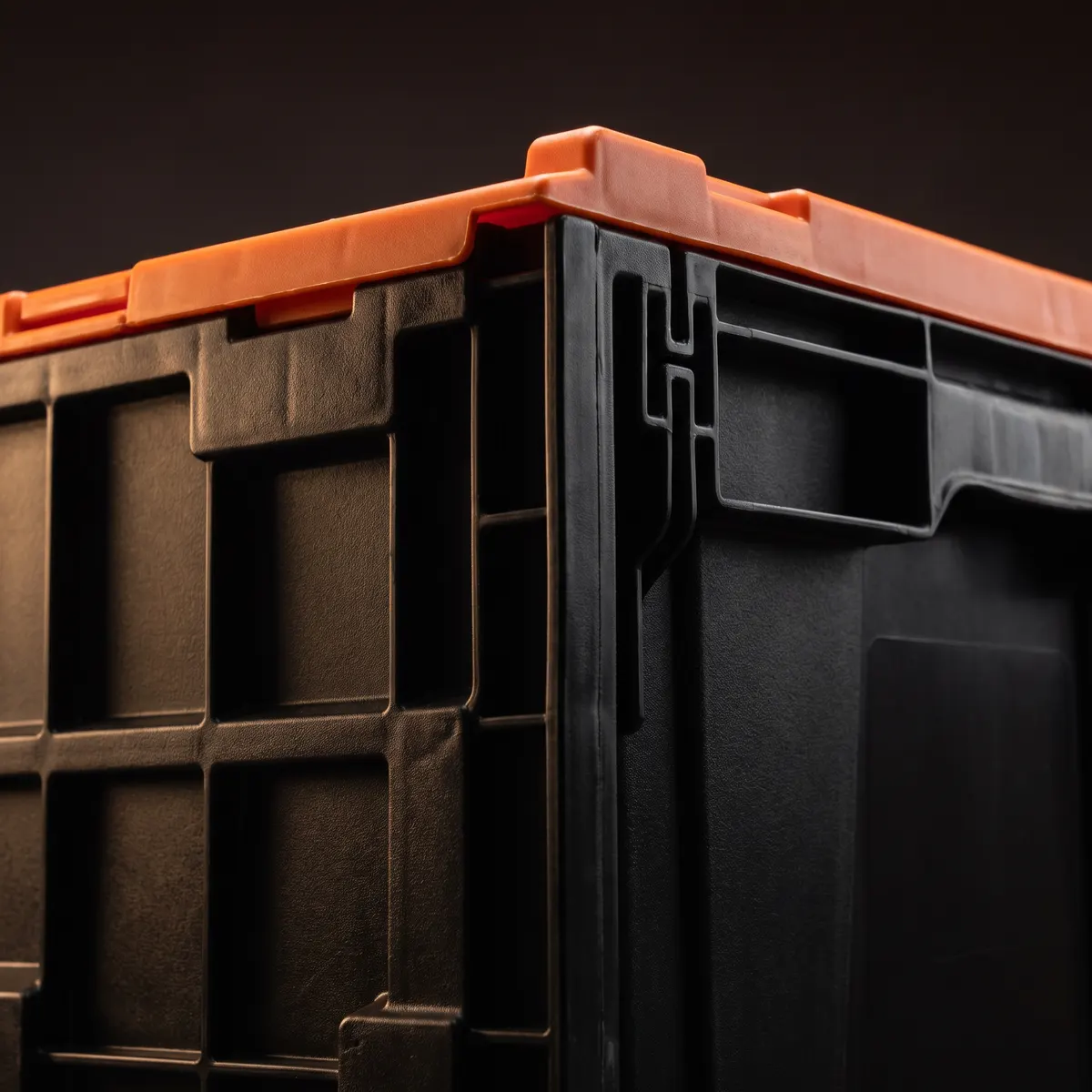 Corner detail of a black heavy-duty moving crate with an orange attached lid